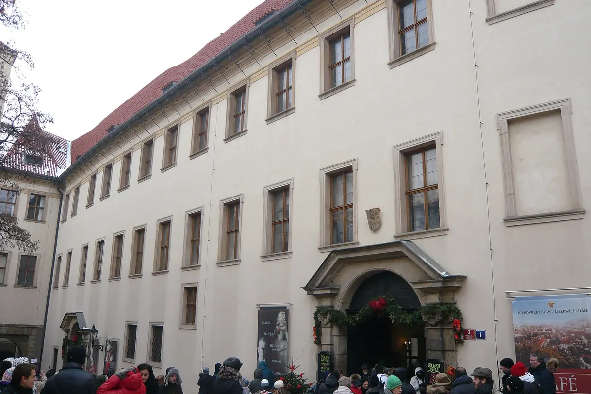 The long pale facade of the Lobkowicz Palace on Jiřská Street with its stone entrance portal.