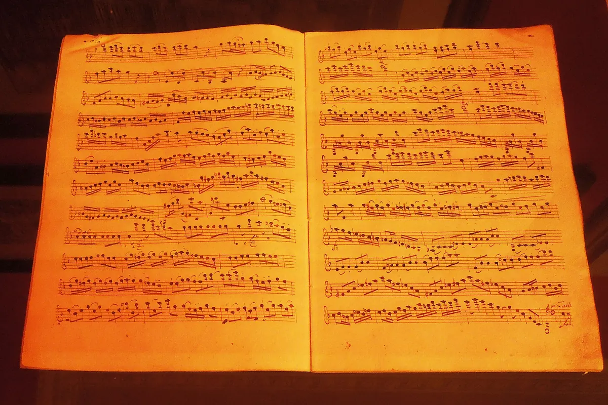 An open spread of a handwritten musical score lit in orange, from the Lobkowicz Collections.